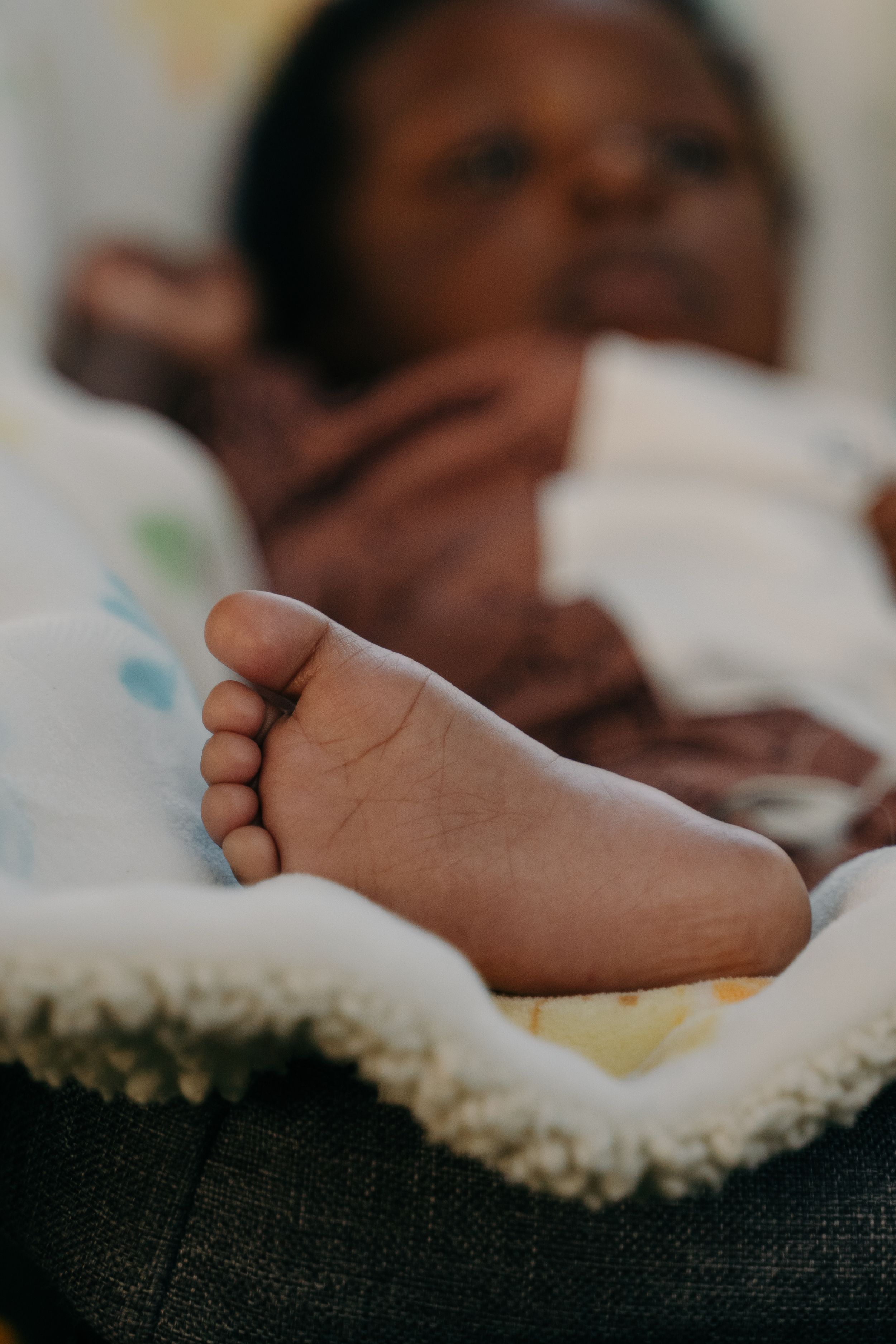 A close-up of a newborn baby's foot resting on a soft blanket